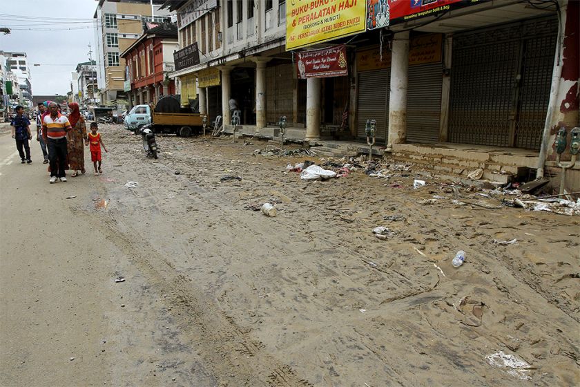 People walk past a mud- and thrash-filled street in Kota Baru as flood levels begin to subside in Kelantan, December 30, 2014. u00e2u20acu201d Picture by Yusof Mat Isa