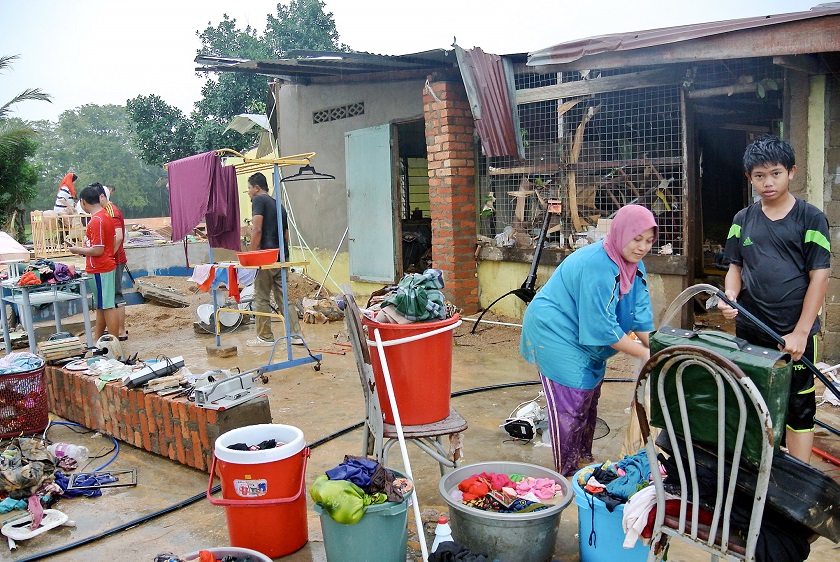Nur Hakimah Abdullah (second from right) cleans furniture and other household items damaged  after the floods at Kampung Kuala Pertang, Mengkebang in Kelantan, December 21, 2014. u00e2u20acu201d Bernama pic