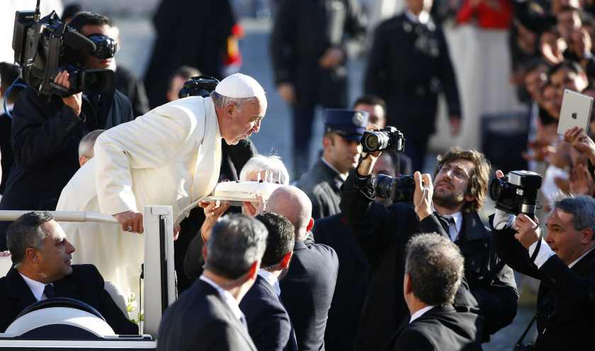 Pope Francis, whose 78th birthday is today, blows out candles on a cake as he arrives to lead his general audience at the Vatican. u00e2u20acu201d Reuters pic