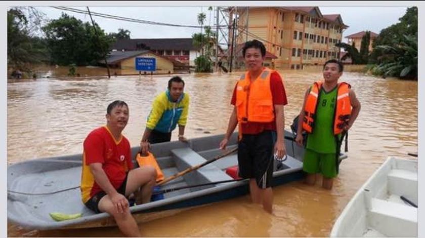Ryonn Leong's brother (in green) with friends going around in a boat to distribute food and help. u00e2u20acu2022 Picture courtesy of Ryonn Leong
