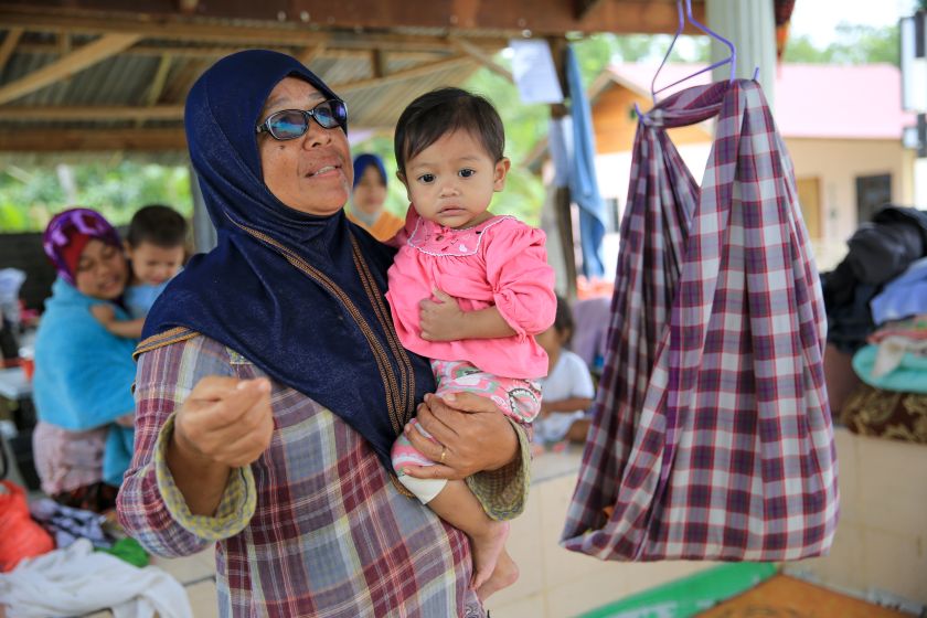 Siti Faridah carrying her one-year-old granddaughter, speaks to the media at an evacuation centre in Kuala Kerai. ― Picture by Saw Siow Feng