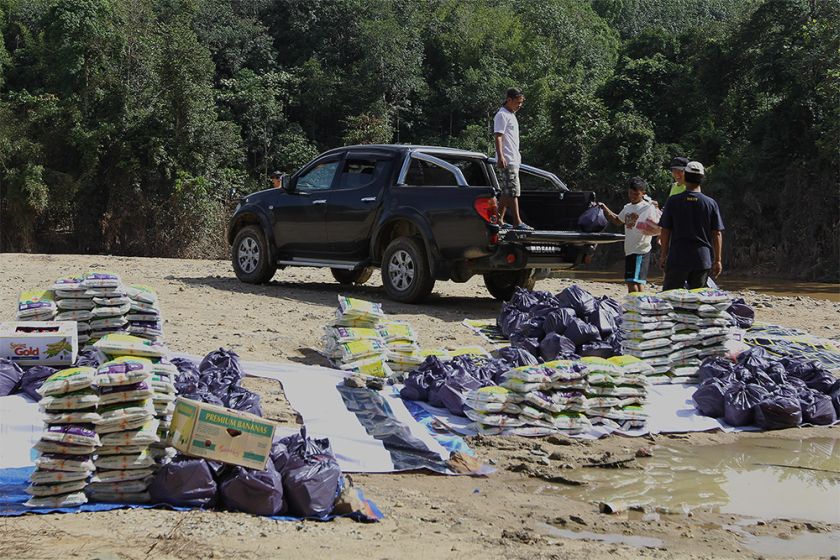 Volunteers help carry and arrange flood aid to the Orang Asli village in Gua Musang.