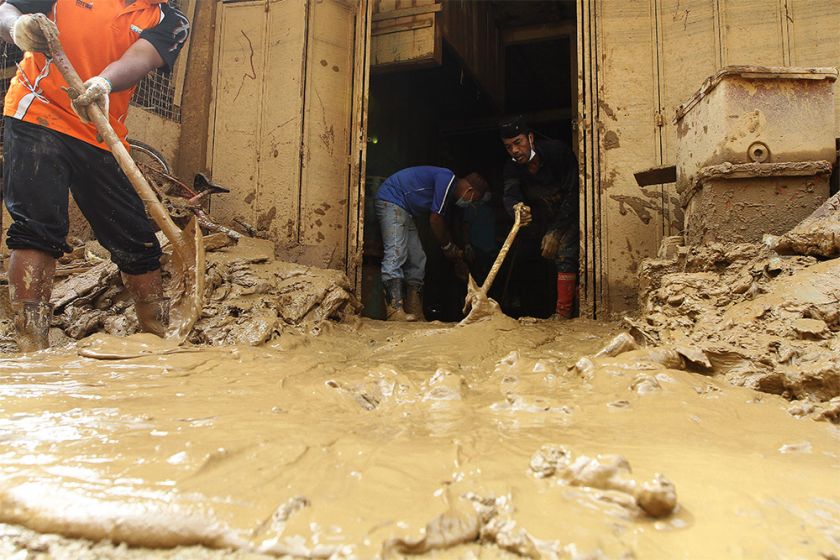 Residents and volunteers are seen shovelling mud out from the houses. 