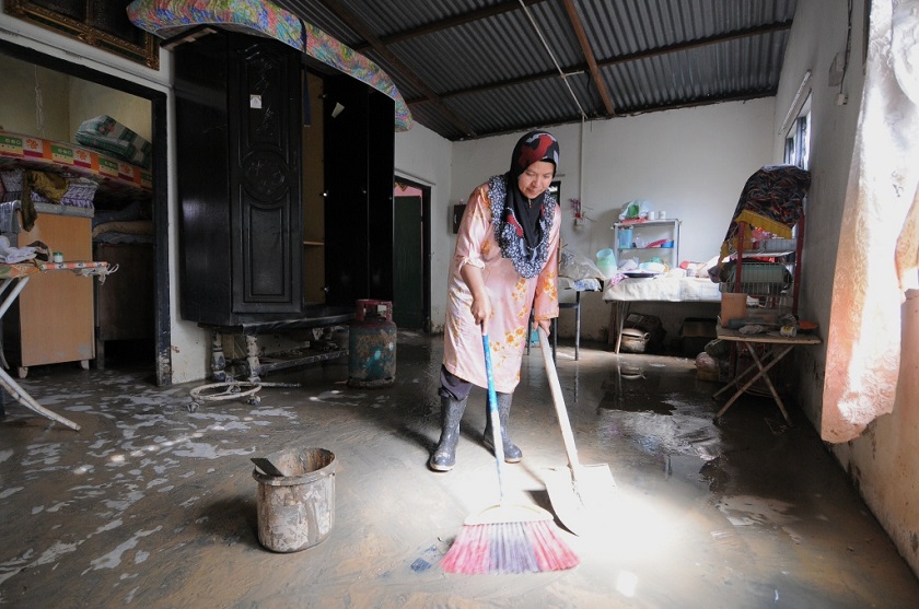 Wan Hasnah Hassan sweeps away the sludge covering the floor of her house in Kampung Senggang in Kuala Kangsar, Perak, January 2, 2015. ― Picture by K.E. Ooi