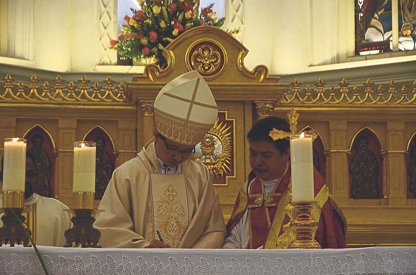 Leow (left) signs a certificate with information on the altar during massu00c2u00a0on Saturday. Chua is next to him. u00e2u20acu201d Picture by Malay Mail