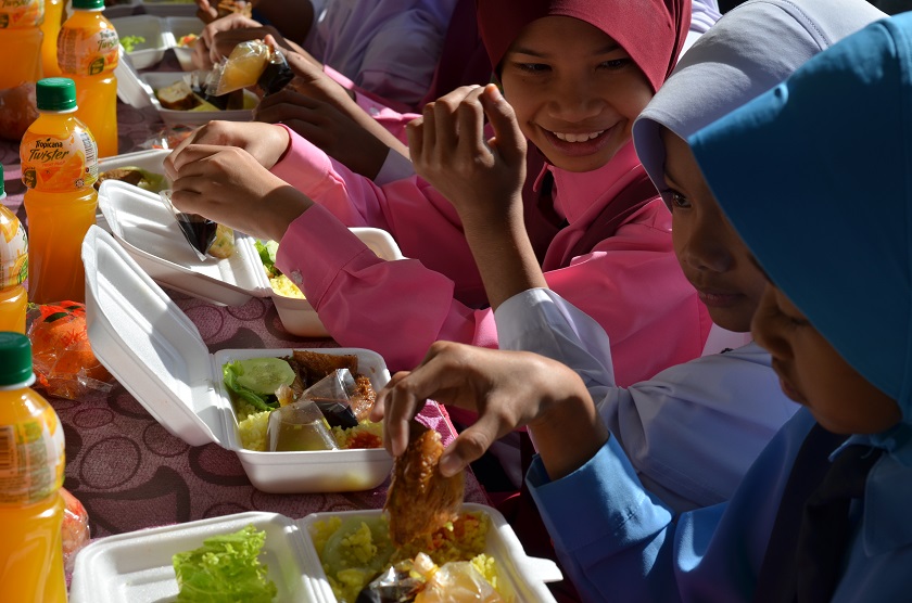 Students tucking into their meal at SK Seberang Pasir Mas, one of the schools hit by the floods last year.