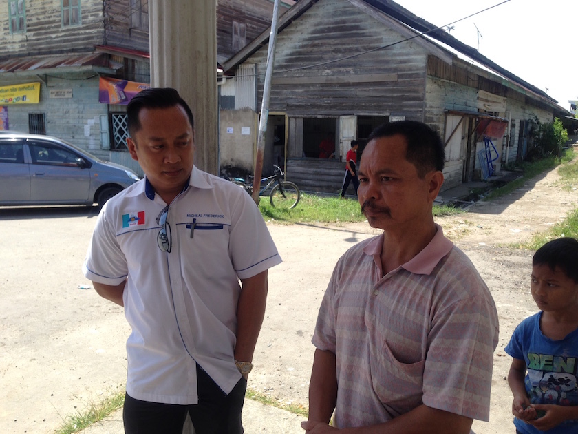 Jilius Yapoo talks to his village development and security chairman Michael Frederick after visiting SMK Kinarut and was told the school would send his four children, residing at the school's hostel, home for the day. u00e2u20acu201d Picture by Julia Chan