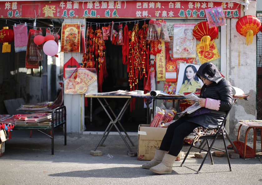 A vendor, selling traditional decorations for the upcoming Chinese Lunar New Year, reads a newspaper as she waits for customers at a migrant workersu00e2u20acu2122 village in Beijing February 12, 2015. u00e2u20acu201d Reuters pic