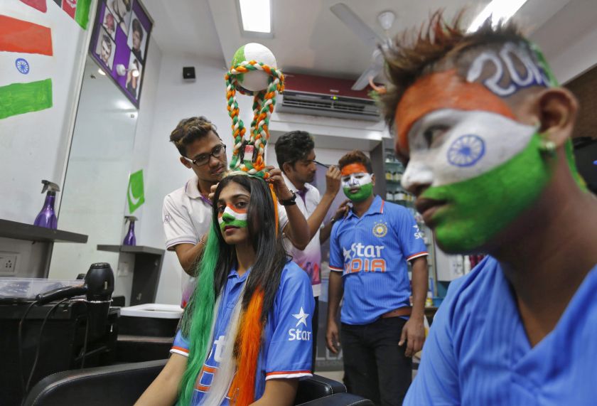 A hairdresser attaches a replica of the Cricket World Cup trophy, which consists of silicone hair, on the head of cricket fan at a saloon during a promotional event in Mumbai February 12, 2015. u00e2u20acu201d Reuters pic