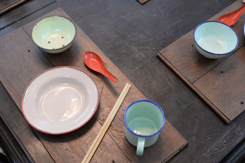 Enamel plates and cups on the dining table at Han Chin Pet Soo. 