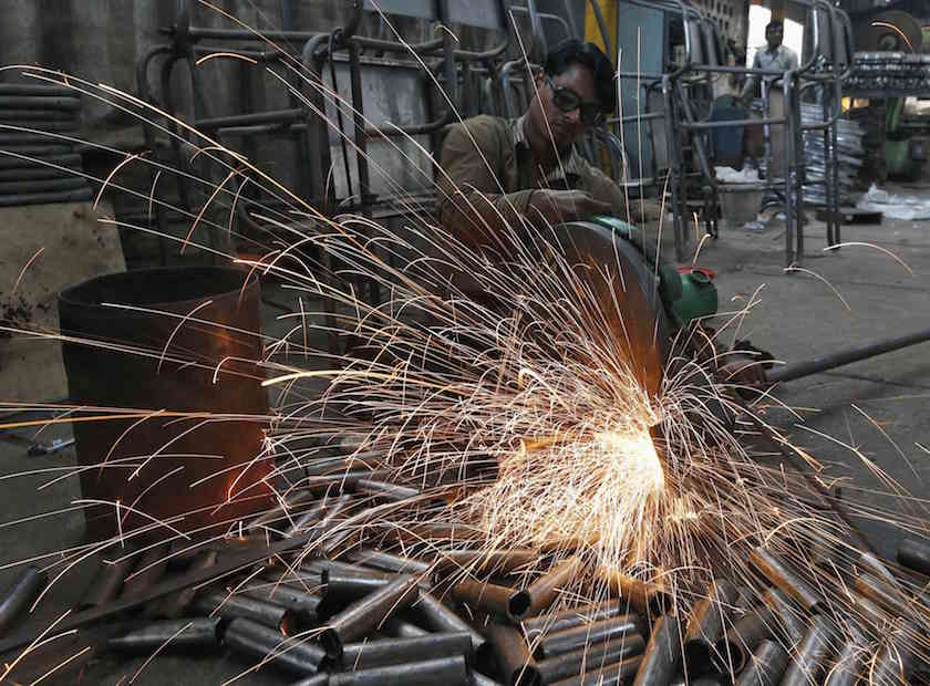 A worker cuts a metal pipe inside a steel furniture production factory in the western Indian city of Ahmedabad February 2, 2015. u00e2u20acu201d Reuters pic