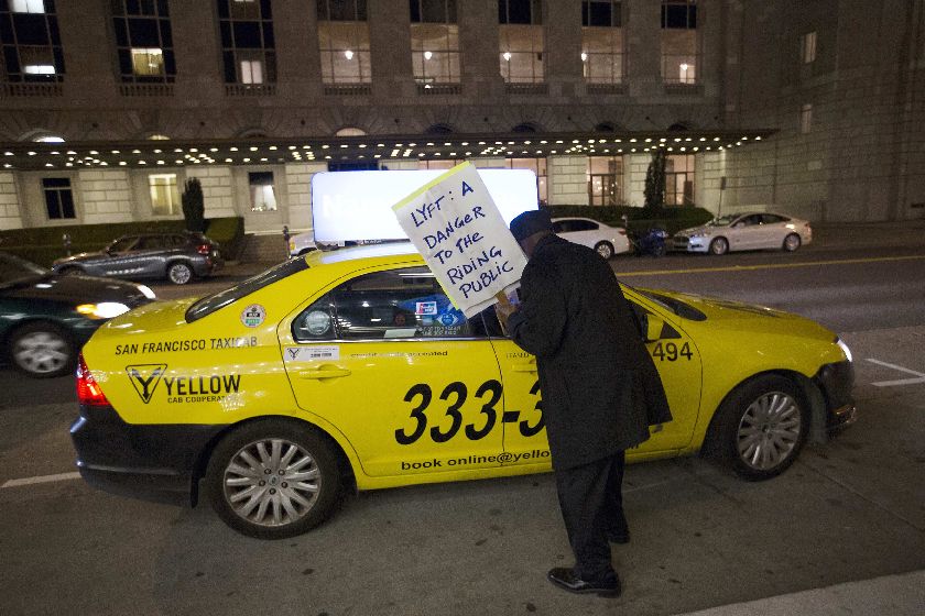 A demonstrator with the San Francisco Taxi Workers Alliance speaks with a taxi driver during a protest against ridesharing services Uber and Lyft outside the 8th Annual Crunchies Awards in San Francisco, February 5, 2015. REUTERS/Stephen Lam 