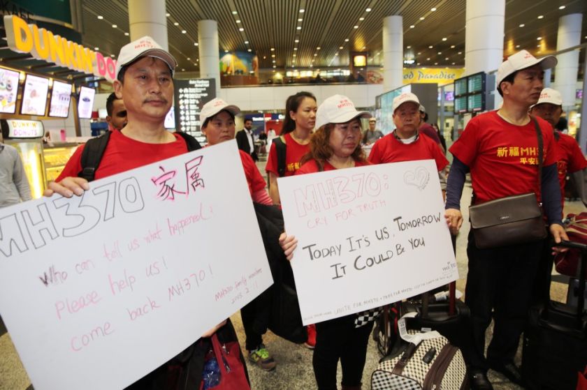 Families of MH370u00e2u20acu2122s Chinese victims hold up play cards after arriving at the Kuala Lumpur International Airport, February 12, 2015. u00e2u20acu201d Picture by Choo Choy May