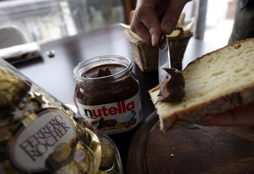 A woman spreads Nutella on a slice of bread in Milan November 20, 2009. There's uncertainty whether the Ferrero family, who owns the maker of Nutella spread, will hold on to the chocolate empire. u00e2u20acu201d Reuters pic