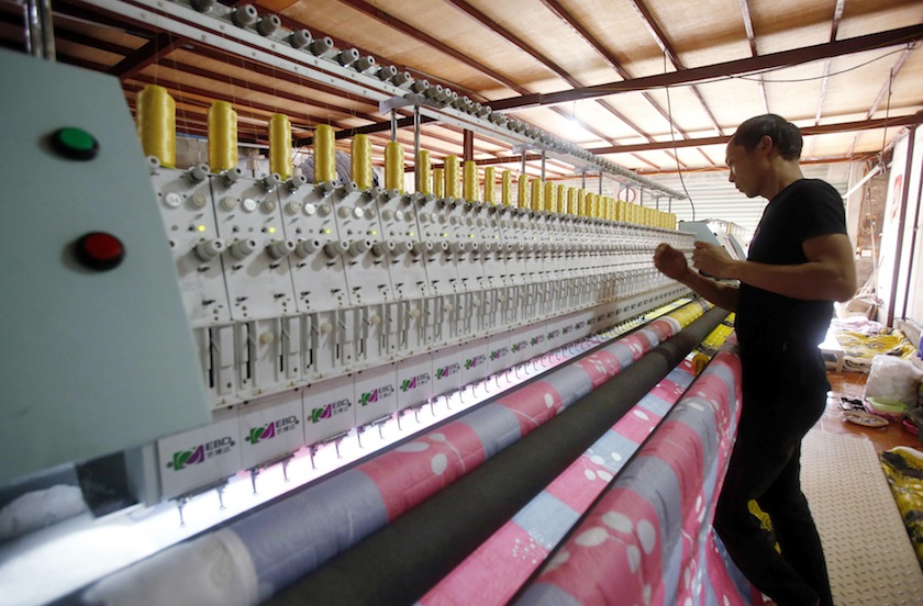 A man works with a made in China quilting embroidery machine at a factory producing blankets, sheets, pillows and cushions at a village outside Hanoi January 27, 2015. u00e2u20acu201d Reuters pic