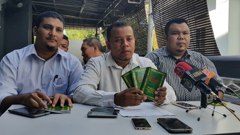 Balik Pulau Umno Youth chief Hisham Abdul Hamid (centre) showing the 'Al Masih' booklets at the press conference this morning.