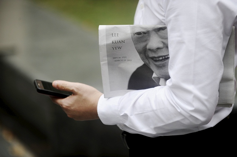 A man holds a newspaper bearing the image of Singapore's former prime minister Lee Kuan Yew, as he checks his phone at Raffles Place in Singapore, March 23, 2015. u00e2u20acu201d Reuters pic