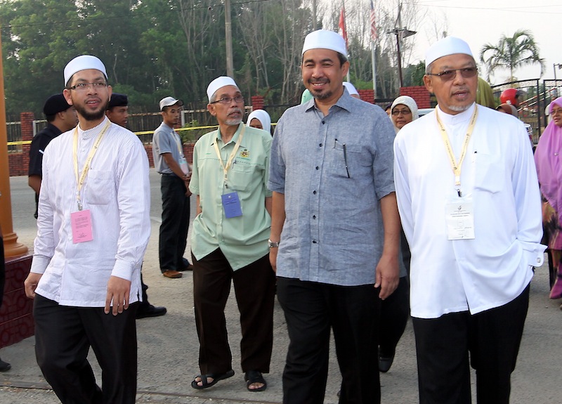 PAS candidate Ahmad Fathan Mahmood @ Mahamad (left) is escorted by  Menteri Besar Kelantan Datuk Ahmad Yakob (kanan) at SMK Pengkalan Chepa 1 during the Chempaka by-election, march 22, 2015. u00e2u20acu201d Bernama picture 
