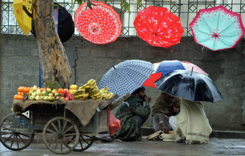 Pakistani vendors eating food at the roadside during a rain shower in Islamabad on March 8, 2015. u00e2u20acu201d AFP pic