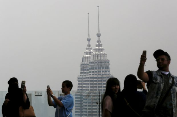 Visitors take u00e2u20acu02dcselfiesu00e2u20acu2122  in front of Malaysiau00e2u20acu2122s landmark Petronas Towers in Kuala Lumpur, March 21, 2015. u00e2u20acu201d Reuters pic