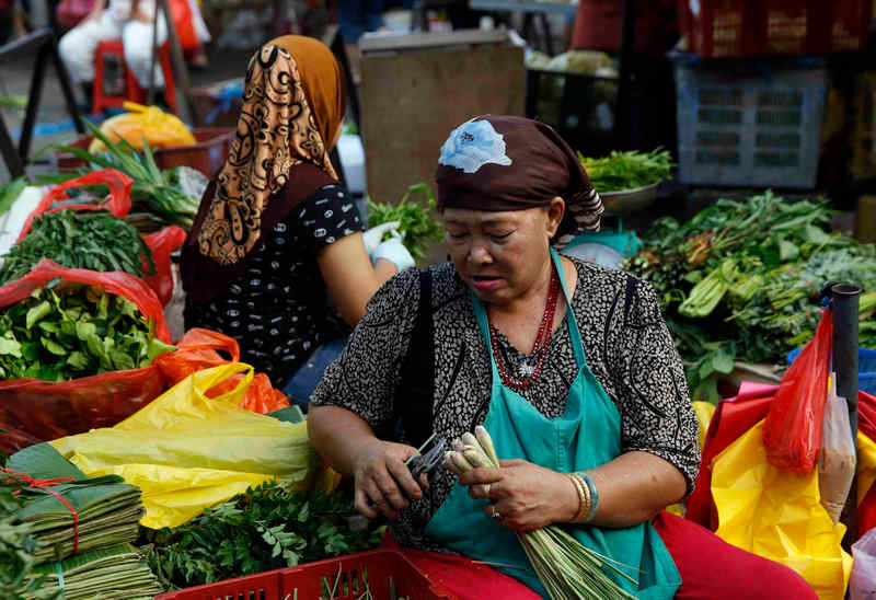 Women trim vegetables in a market in Kuala Lumpur March 3, 2015. Malaysia's inflation data for February has been delayed for two days by the Statistics Department. u00e2u20acu201d Reuters pic