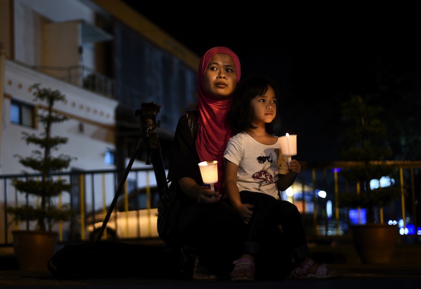 A young Malaysian girl sits in her mother's lap during a gathering to mark the one-year anniversary of the disappearance of Malaysia Airlines flight MH370, in Kuala Lumpur on March 6, 2015. u00e2u20acu201du00c2u00a0AFP pic