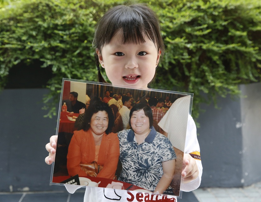 Jie Yie, four years old, holds a picture of her grandmother Lee Sew Chu and her aunt Ng May Li who were aboard missing Malaysia Airlines flight MH370, on the one year anniversary of its disappearance at a remembrance event, in Kuala Lumpur, March 8, 2015.