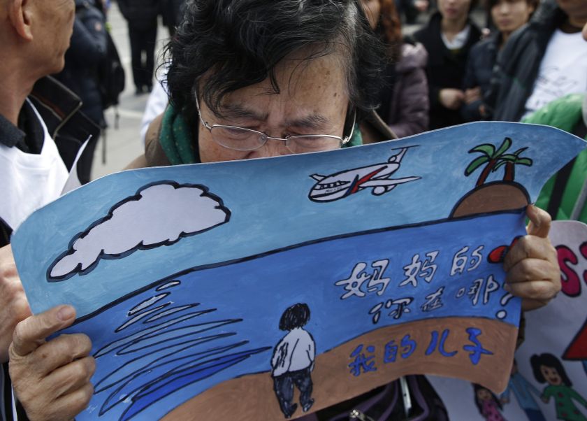 Wang Guohui, mother of a passenger of the missing Malaysia Airlines flight MH370, cries while holding a painting which her family made for wishing the return of her son in Beijing March 8, 2015. u00e2u20acu2022 Reuters pic