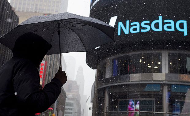 A man uses an umbrella to guard against snowfall as he walks past the Nasdaq MarketSite in Times Square, Midtown New York March 20, 2015. u00e2u20acu201d Reuters pic