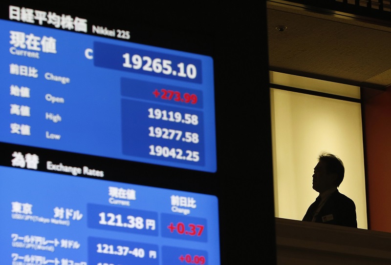 A man stands next to a stock quotation board displaying Japanu00e2u20acu2122s Nikkei Average (top) and the exchange rates between the Japanese yen and the US dollar at the Tokyo Stock Exchange in Tokyo, March 13, 2015. u00e2u20acu201d Reuters pic