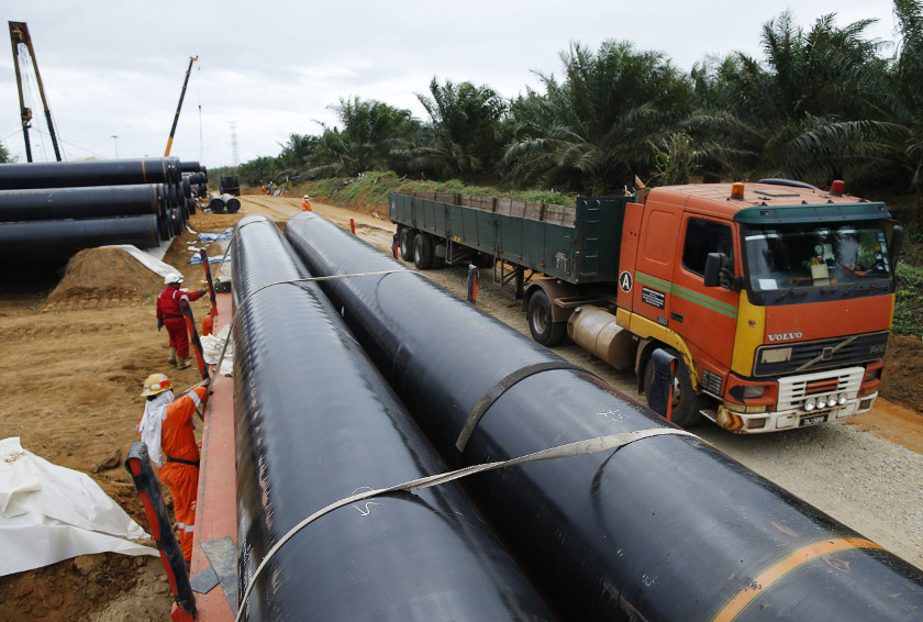 Workers transport oil pipelines to be laid for the Pengerang Gas Pipeline Project at an area 40km away from the Pengerang Integrated Petroleum Complex in Pengerang, Johor, February 4, 2015. u00e2u20acu201d Reuters pic