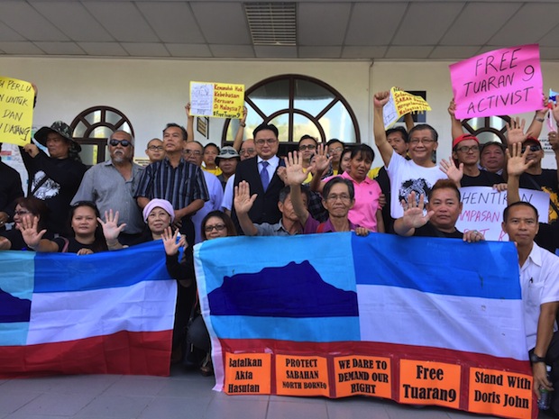 Supporters of the four accused at the court carryingu00c2u00a0the Sabah flag, and signs bearing the words 'Free Tuaran 9 activist and calling for freedom of expression and Sabah rights to be restored.n