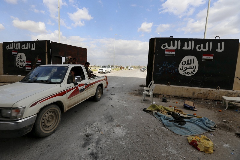 Shi'ite paramilitary fighters ride a vehicle past a wall painted with the black flag commonly used by Islamic State militants, near former Iraqi president Saddam Hussein's palace in Tikrit April 1, 2015. u00e2u20acu201d Reuters pic