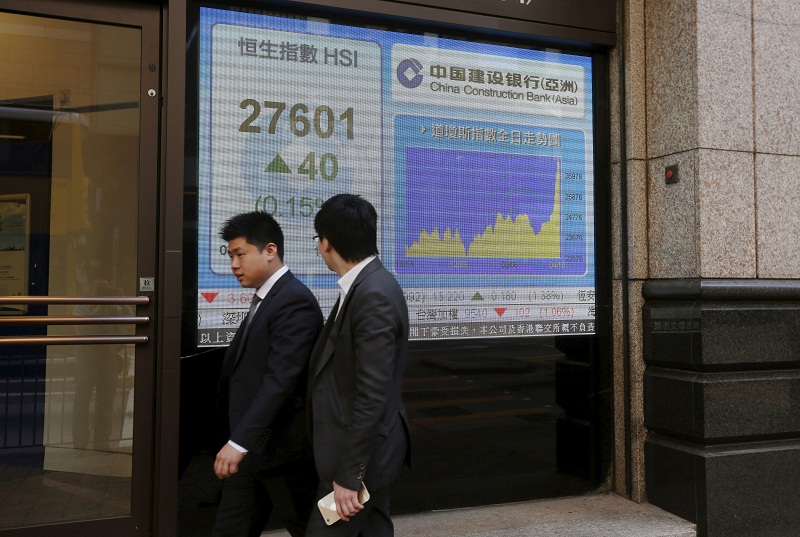 People walk past a panel displaying the benchmark Hang Seng Index during afternoon trading outside a bank in Hong Kong April 15, 2015. u00e2u20acu201d Reuters pic