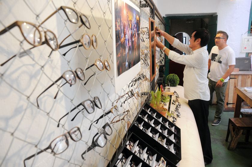 A customer choosing a pair of wooden frame sunglasses of The sea is our playground range at Spark Optics. — Picture by K.E.Ooi