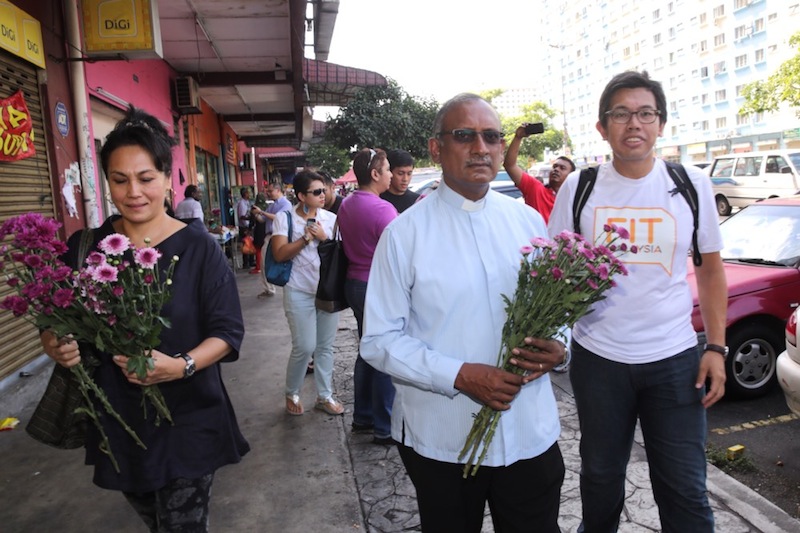 Azrul Mohd Khalid (right) and Council of Churches Malaysia general secretary Rev Dr Herman Shastri walking at the flats area to give away flowers. u00e2u20acu201d Picture by Choo Choy May