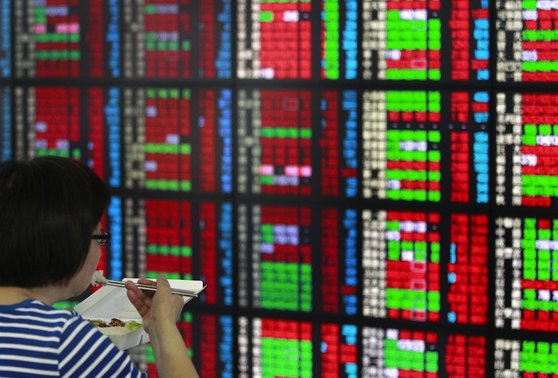 A woman eats her lunch from a food box while monitoring stock market prices inside a brokerage in Taipei, Taiwan, April 24, 2015.u00c2u00a0u00e2u20acu201d Reuters pic