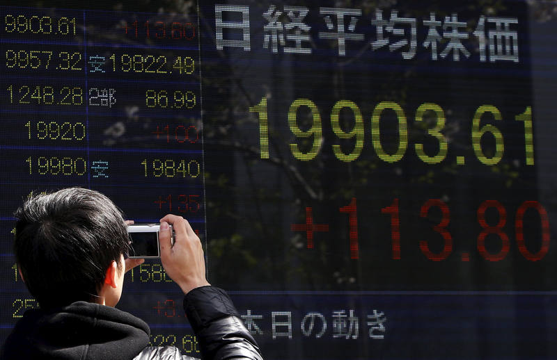 A pedestrian takes pictures of an electronic board showing the Japan's nikkei average in Tokyo April 9, 2015. The Nikkei hit a 15-year peak this morning (April 22, 2015). u00e2u20acu201d Reuters pic