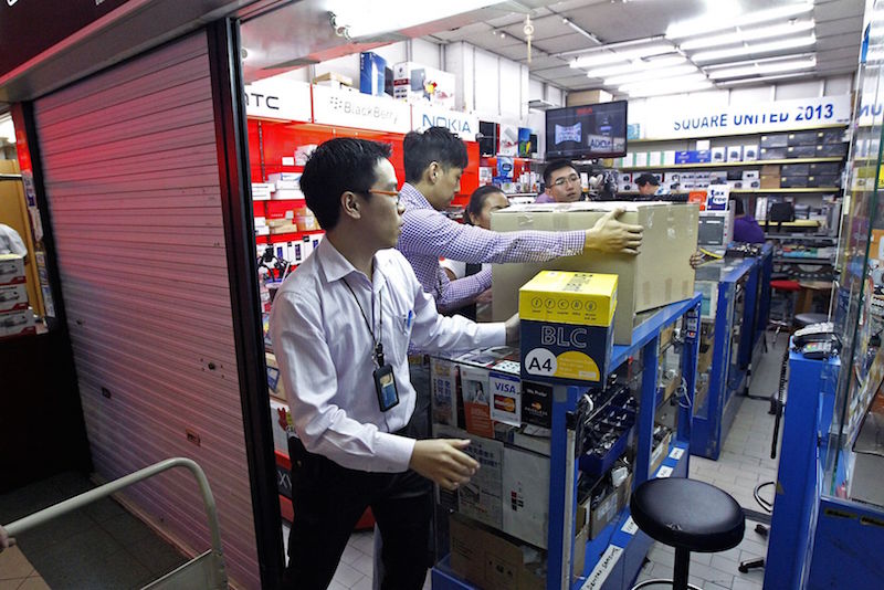 Singapore police officers leave with sealed boxes after they raided a shop at Sim Lim Square on December 4, 2014. u00e2u20acu201d Today pic 