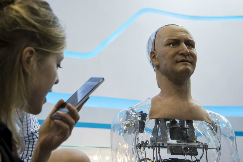 A staff member talks to a humanoid robot developed by Hanson Robotics via a mobile phone during the Global Sources electronics show in Hong Kong April 19, 2015. The robotu00e2u20acu2122s skin is made of elastic polymer material that mimics the human skin. u00e2u20acu201d Reuters