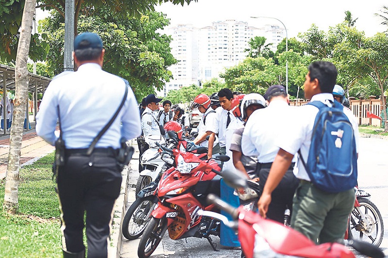 Traffic police officers check the particulars of some of the students who rode motorcycles to school during the Ops Roda Sekolah at SMK Datou00e2u20acu2122 Lokman yesterday. u00e2u20acu201d Picture by Ahmad Zamzahuri