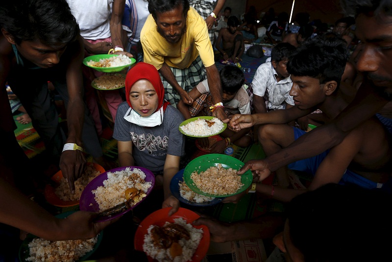 Bangladeshi migrants, who recently arrived in Indonesia by boat, raise up their plates to ask for more food, as breakfast is served by An Indonesian volunter at a shelter in Kuala Langsa, in Indonesia's Aceh Province, May 19, 2015. u00e2u20acu201d Reuters pic