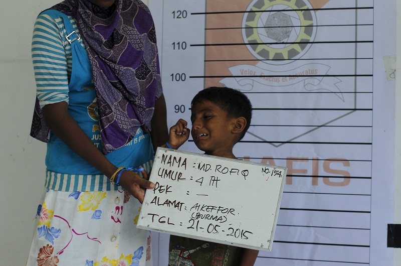 A Rohingya migrant mother, who recently arrived in Indonesia by boat, holds a placard for her son getting a picture taken for identification purposes inside a temporary compound for refugees in Aceh Timur regency, Indonesia‘s Aceh Province May 21, 2015.