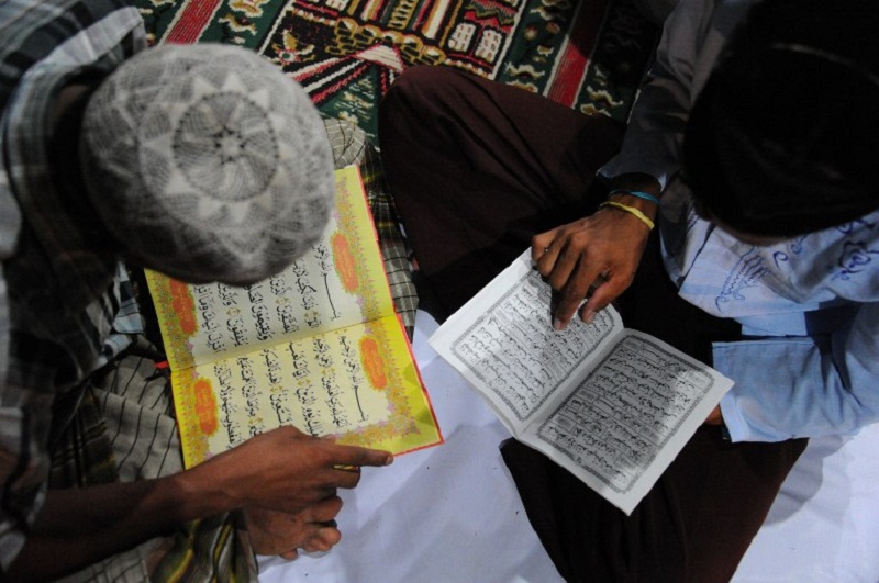 Rohingya men read the Quran at a confinement area for migrants at Kuala Cangkoi, Aceh province, May 25, 2015. u00e2u20acu201d AFP pic