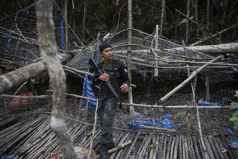 A policeman holds his weapon at abandoned human trafficking camp in the jungle close the Thailand border at Bukit Wang Kelian in northern Malaysia May 26, 2015. u00e2u20acu201d Reuters pic