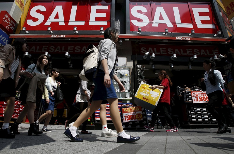 A shop clerk carries a box of shoes under sale signboards at a shoes retail store at a shopping district in Tokyo, Japan, April 28, 2015. u00e2u20acu201d Reuters pic