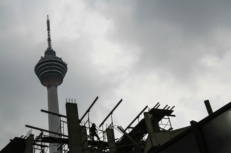 A worker is silhouetted against the sky at a construction site, with the KL Tower in the background, in Kuala Lumpur, May 25, 2015. u00e2u20acu201d Picture by Yusof Mat Isa 