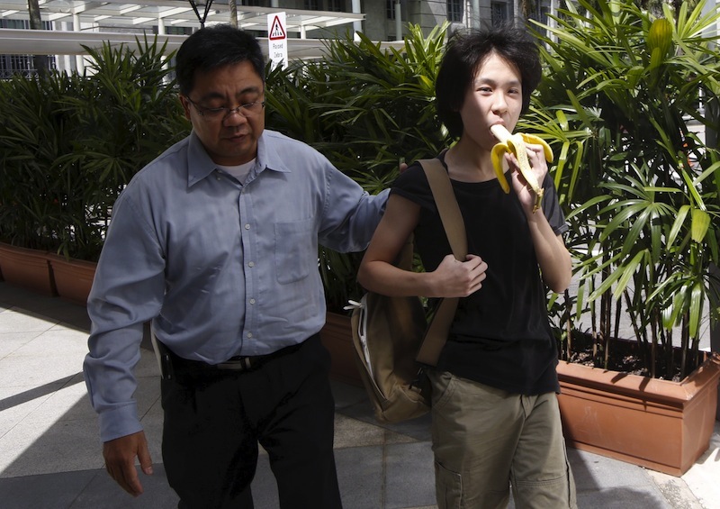 Amos Yee eats a banana as he arrives with his father to the State Courts for a pre-trial conference in Singapore in this file picture taken April 17, 2015. u00e2u20acu201d Reuters pic