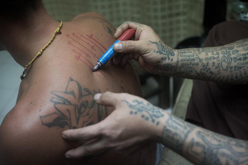 Thai master tattoo artist Arjarn Neng (right) working on a German tourist at his studio in Bangkok, January 29, 2015. u00e2u20acu201d AFP pic