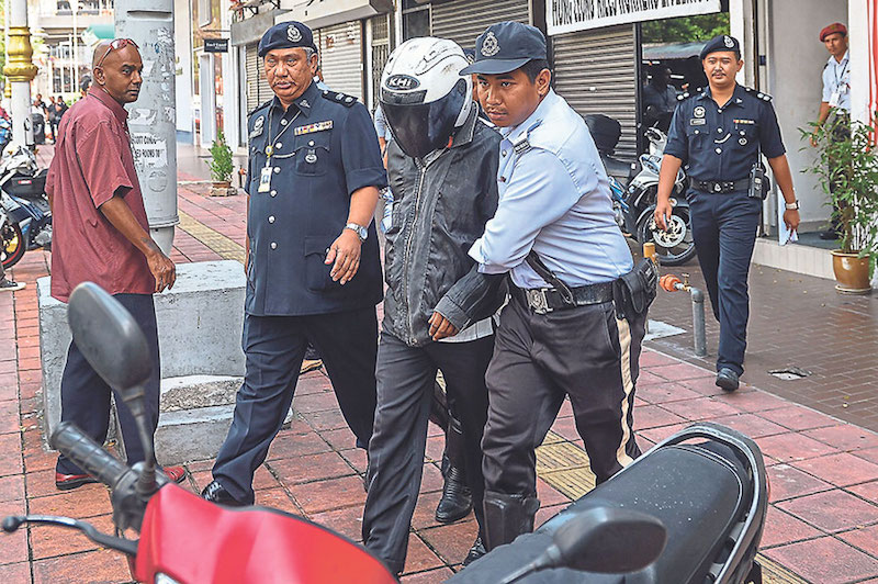 Traffic police arrest an offender who has not settled his summonses during the first day of Ops Warta in Brickfields, Kuala Lumpur, yesterday. u00e2u20acu201d Picture by Firdaus Latif